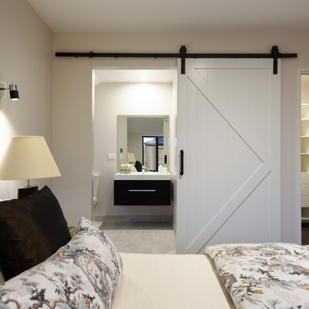New home modern bedroom with ensuite by Deluxe Homes.