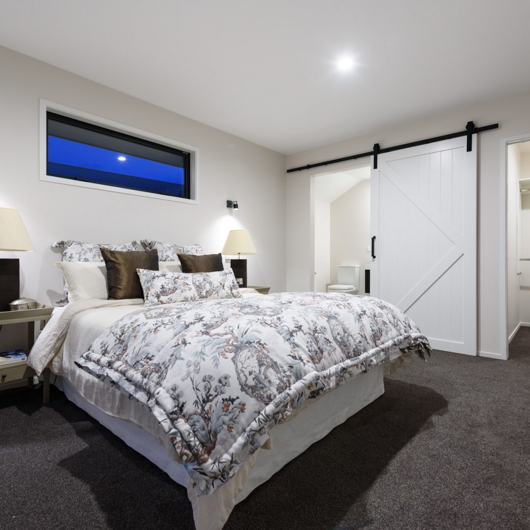 New home bedroom with barn door design, built by Deluxe Homes.